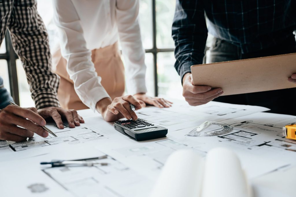 Gros plan sur des mains travaillant en brainstorming et en prenant des mesures pour estimer les coûts sur des documents.